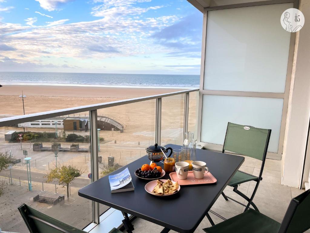 - une table avec une assiette de nourriture sur un balcon donnant sur la plage dans l'établissement Au85, Bel appartement, vue océan, pied de la plage, à Saint-Jean-de-Monts