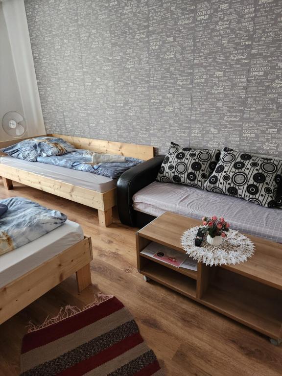 a living room with two beds and a table at ORSI Eco apartman Kecskemét in Kecskemét