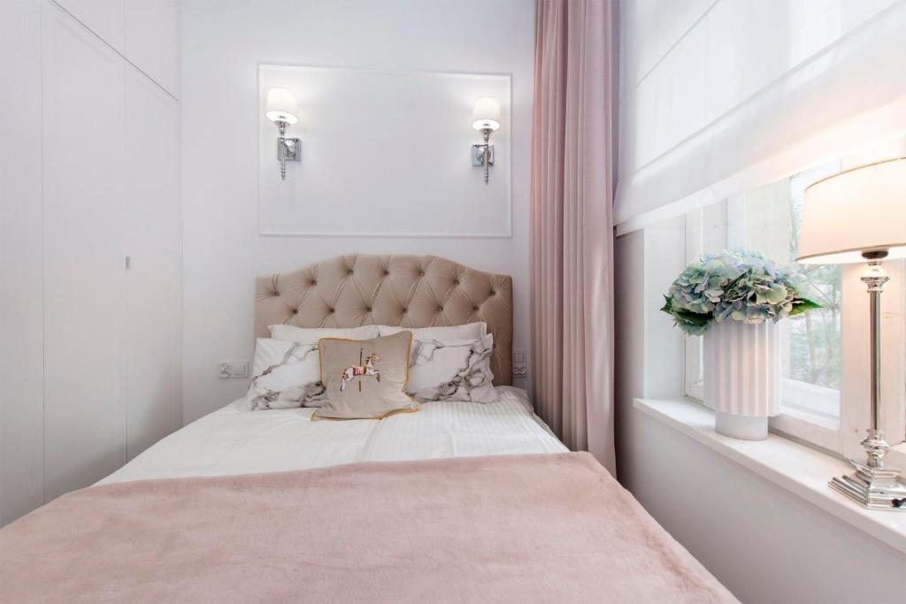 a white bedroom with a large bed with a window at La Boutique Studio Sopot in Sopot