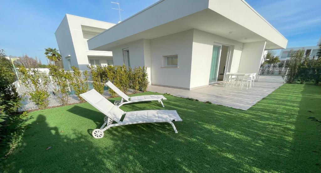 two lounge chairs on a lawn in front of a house at APP4RENT GROUND FLOOR - 2 family apartments in Lido di Jesolo
