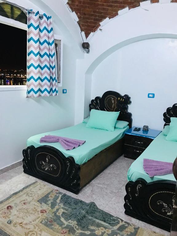 a bedroom with two beds and a window at Gamal Robob Nubian Guest House in Aswan
