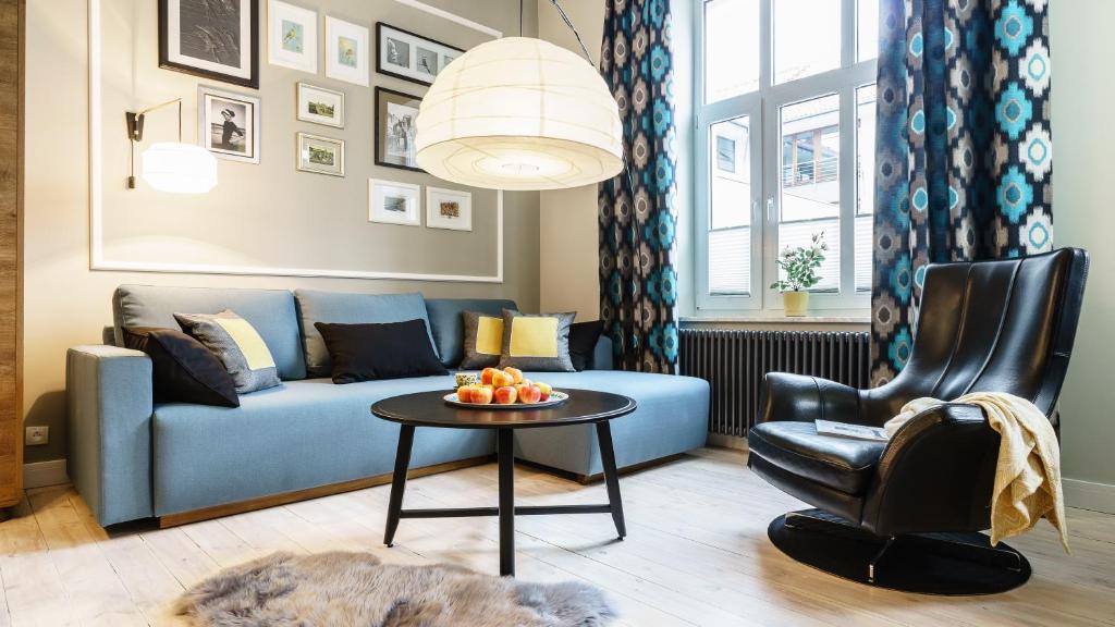 a living room with a blue couch and a table at Sanhaus Apartments - ul HAFFNERA i okolice - 3-5 minut od plaży i deptaka in Sopot