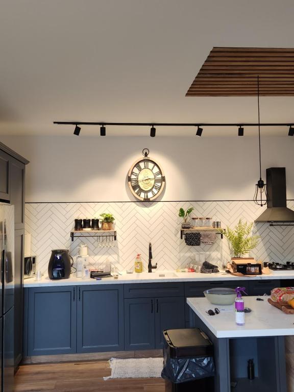 uma cozinha com armários azuis e um relógio na parede em הפנינה האנגלית em Ramla