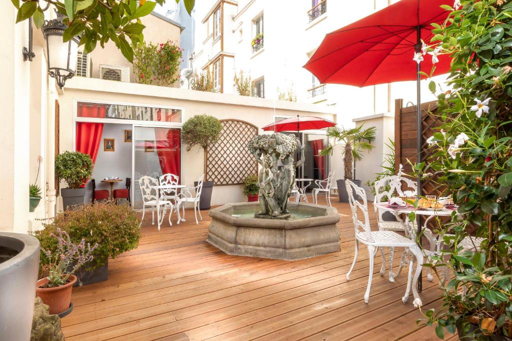 een patio met een fontein, tafels en stoelen en een parasol bij Agate Hôtel in Parijs