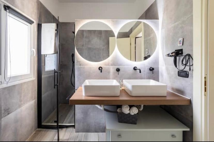 a bathroom with two sinks and a mirror at Aragon Cottage Apartments in Le Castella