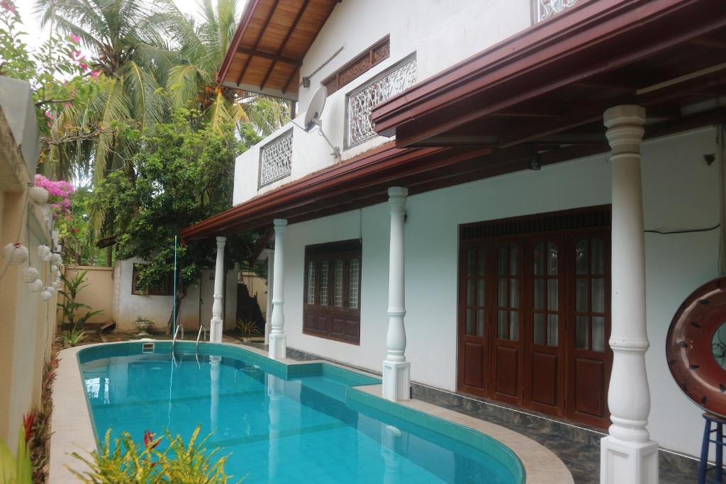 a villa with a swimming pool in front of a house at Mango Tree House in Beruwala
