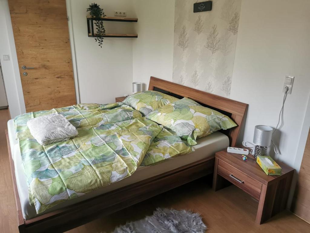 a bed with a comforter and a night stand next to it at HomeW4 - Tiny Apartment in Hoheneich