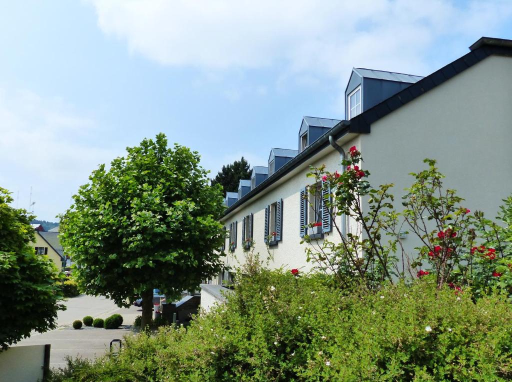 ein weißes Gebäude mit blauen Fensterläden und Bäumen in der Unterkunft Manoir Kasselslay in Clerf