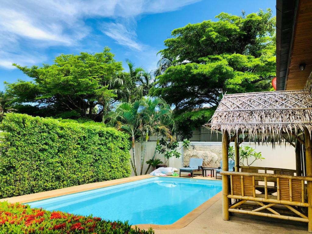 a swimming pool with a chair and a umbrella at Thai family rawai Swimming pool villa Hotel in Rawai Beach