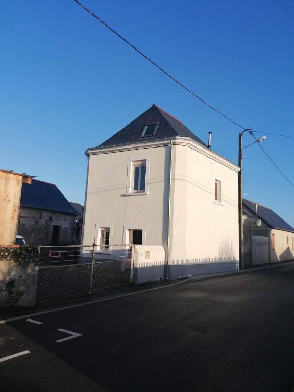 un bâtiment blanc avec un toit noir dans une rue dans l'établissement Gîte des Lilas, 