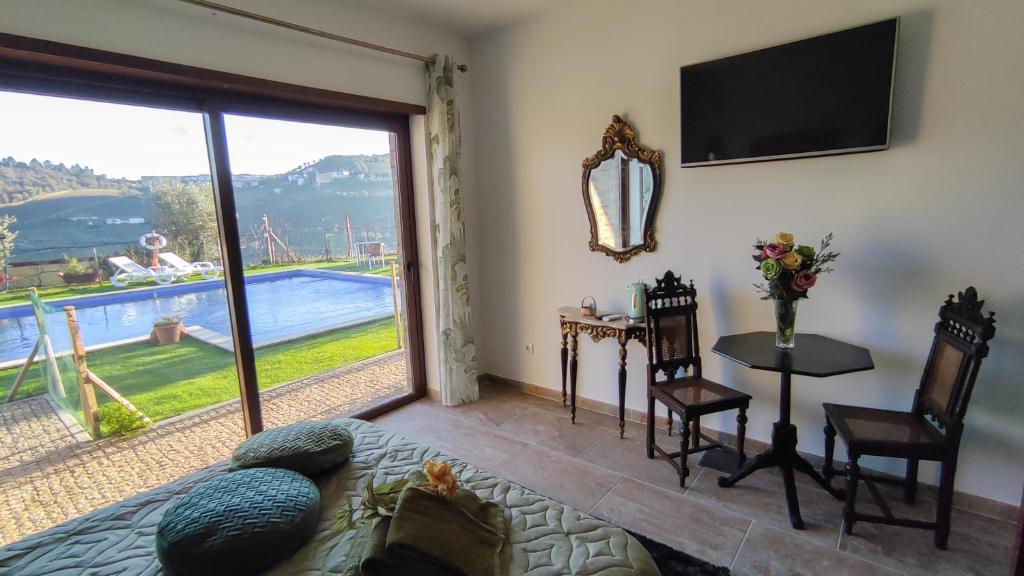 a living room with a tv and a table with chairs at Quinta dos Padrinhos - Suites in the Heart of the Douro in Lamego