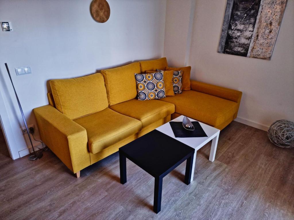 a living room with a yellow couch and a table at Cozy apartment with a fantastic sea view in Cala Millor