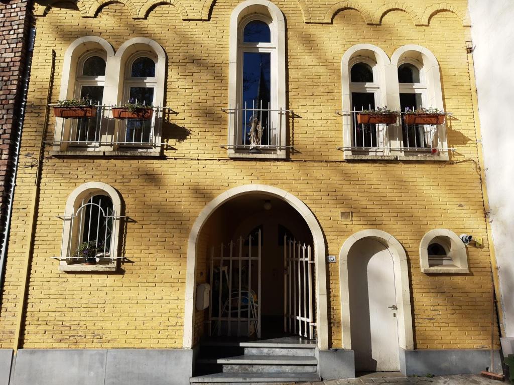um edifício de tijolos amarelos com três janelas e uma porta em Loft in Borgloon em Borgloon