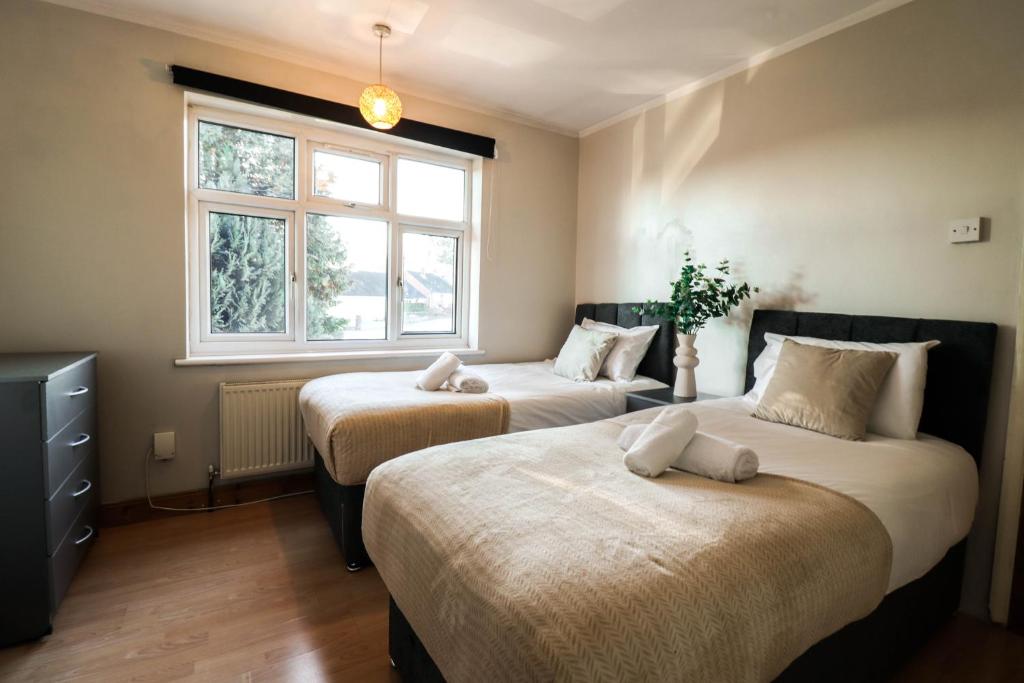 - une chambre avec 2 lits et une fenêtre dans l'établissement Cosy contractor house with FREE parking!, à Luton