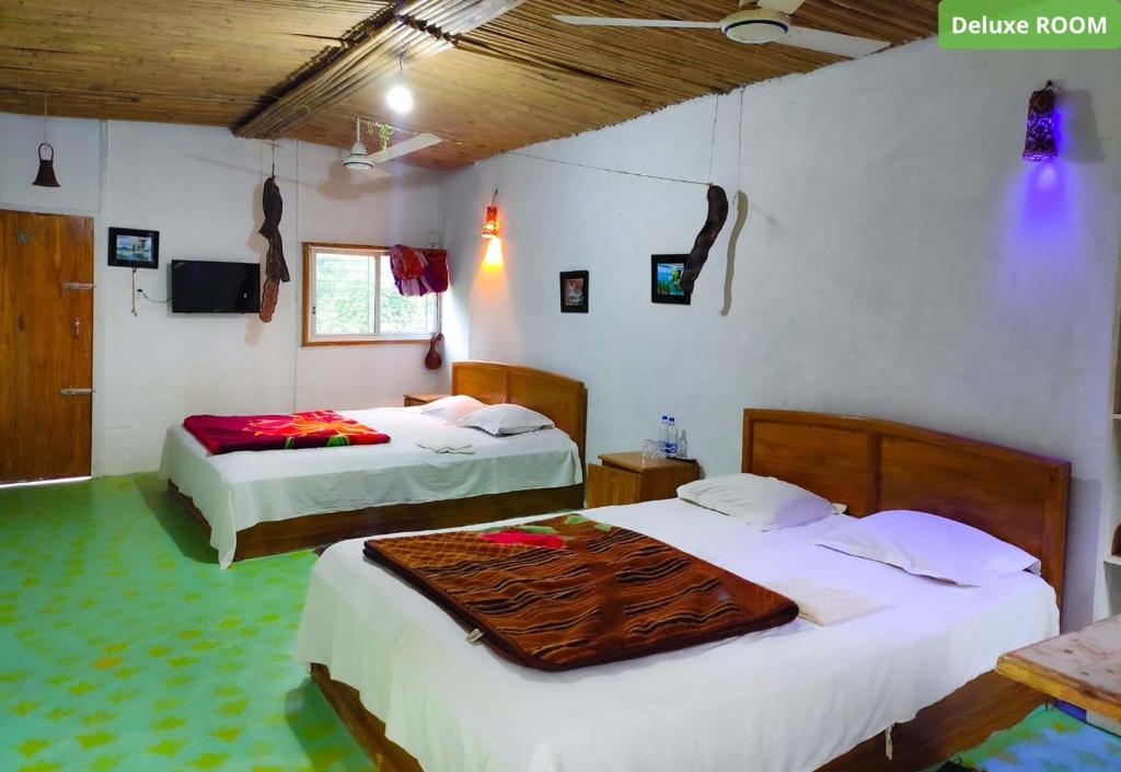 a bedroom with two beds and a television in it at Bono Nibash Hill Resort in Bāndarban