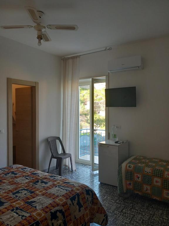 a bedroom with a bed and a chair and a window at Hotel Conca d'Oro in Stalettì