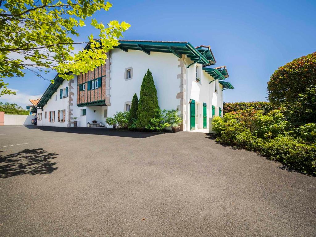 un grand bâtiment blanc avec une grande allée. dans l'établissement Maison d'hôte Iparra- Pays Basque, à Arcangues