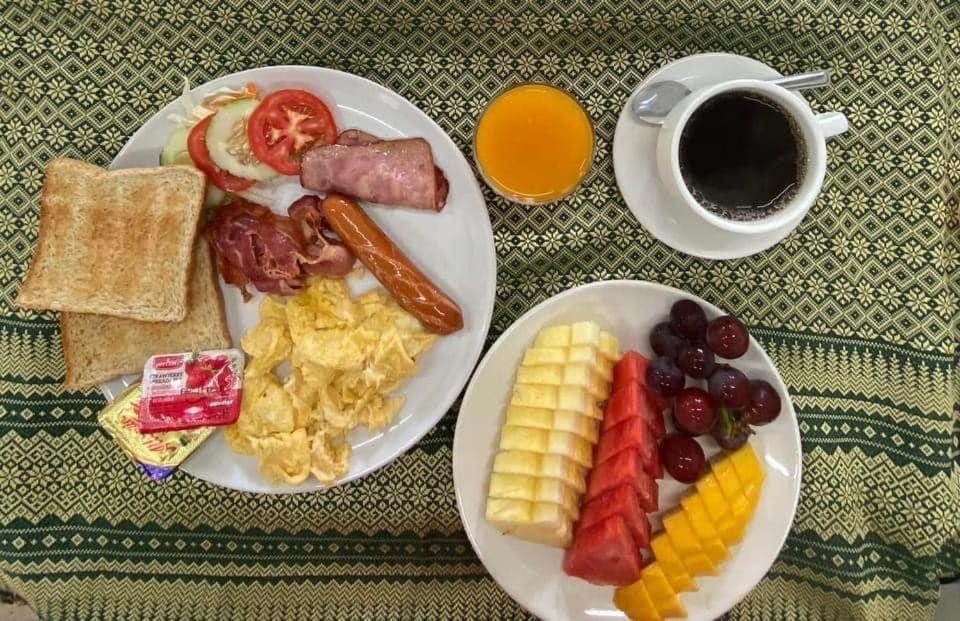 a table with two plates of breakfast food and a cup of coffee at Blue Ba You Resort in Ban Khlong Haeng