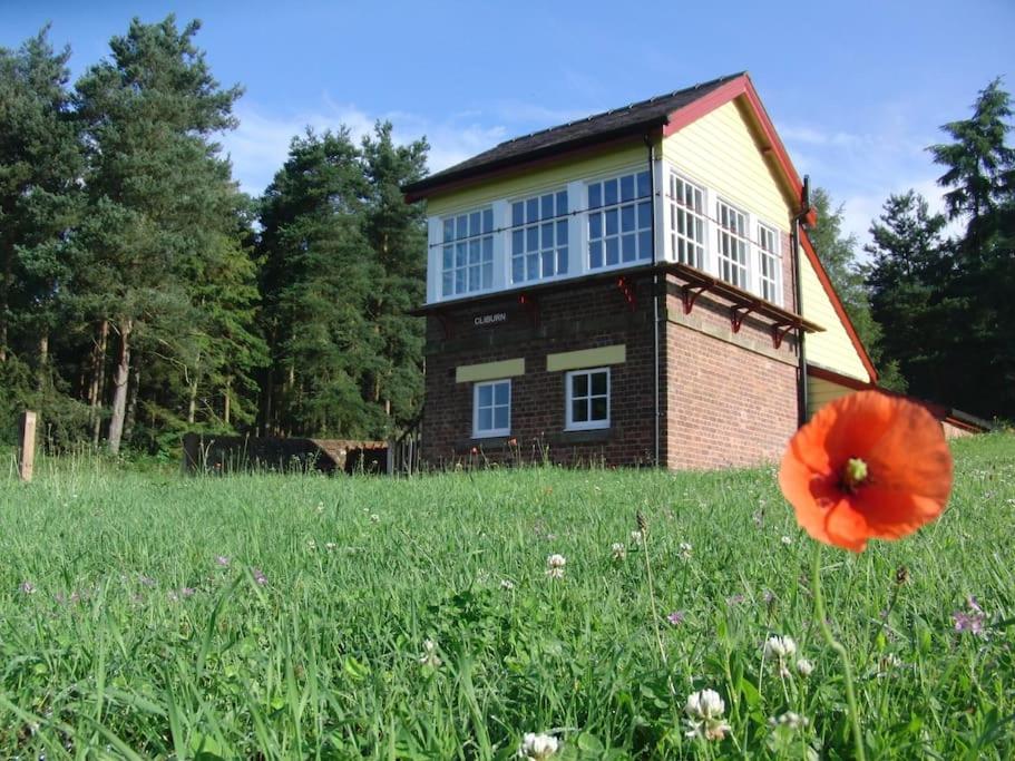 una casa con una flor roja en un campo en The Signal Box (Cliburn) en Penrith