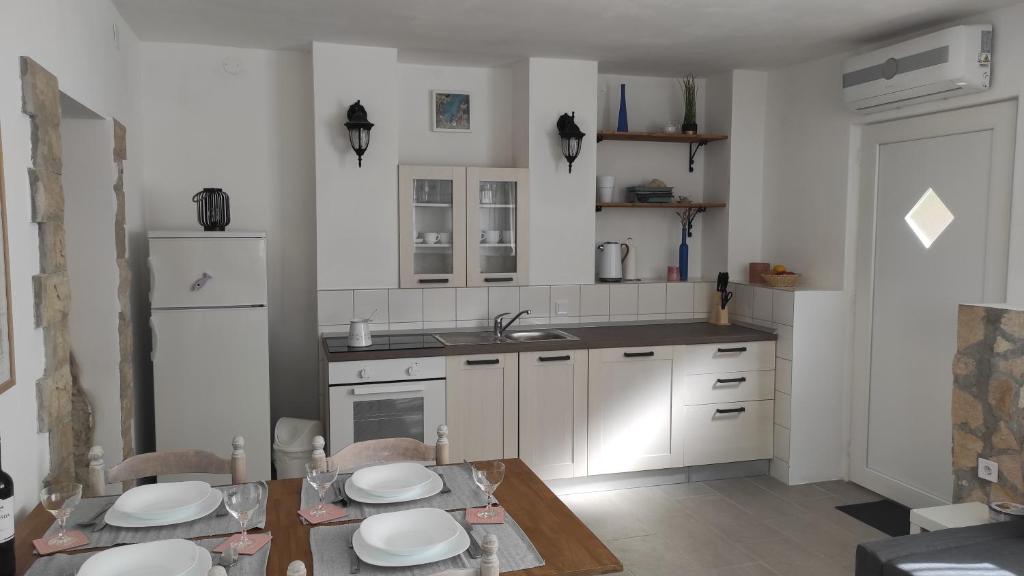 a kitchen with white cabinets and a table with chairs at Apartment Loparina in Nerezine