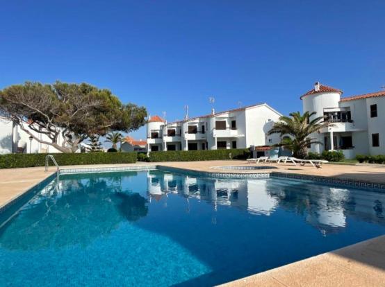 a large blue swimming pool in front of a building at Apartamentos Mar a mar in Cala en Forcat