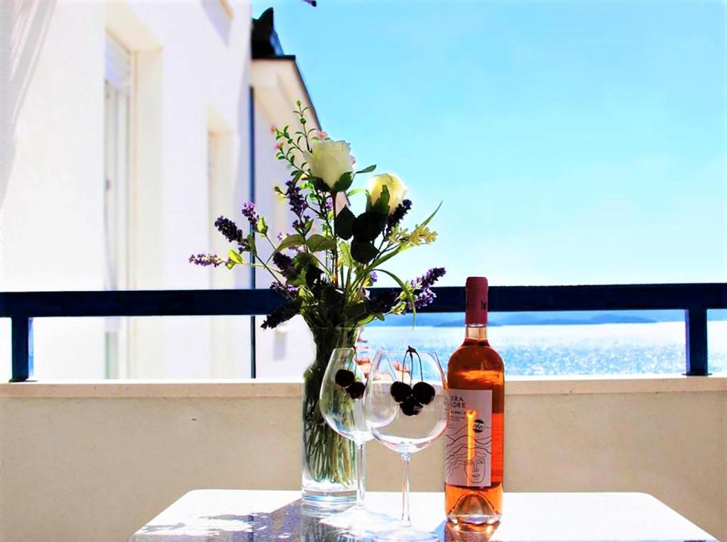 a bottle of wine and a vase of flowers on a table at AG Komarna - Peljesac Bridge Apartments in Komarna