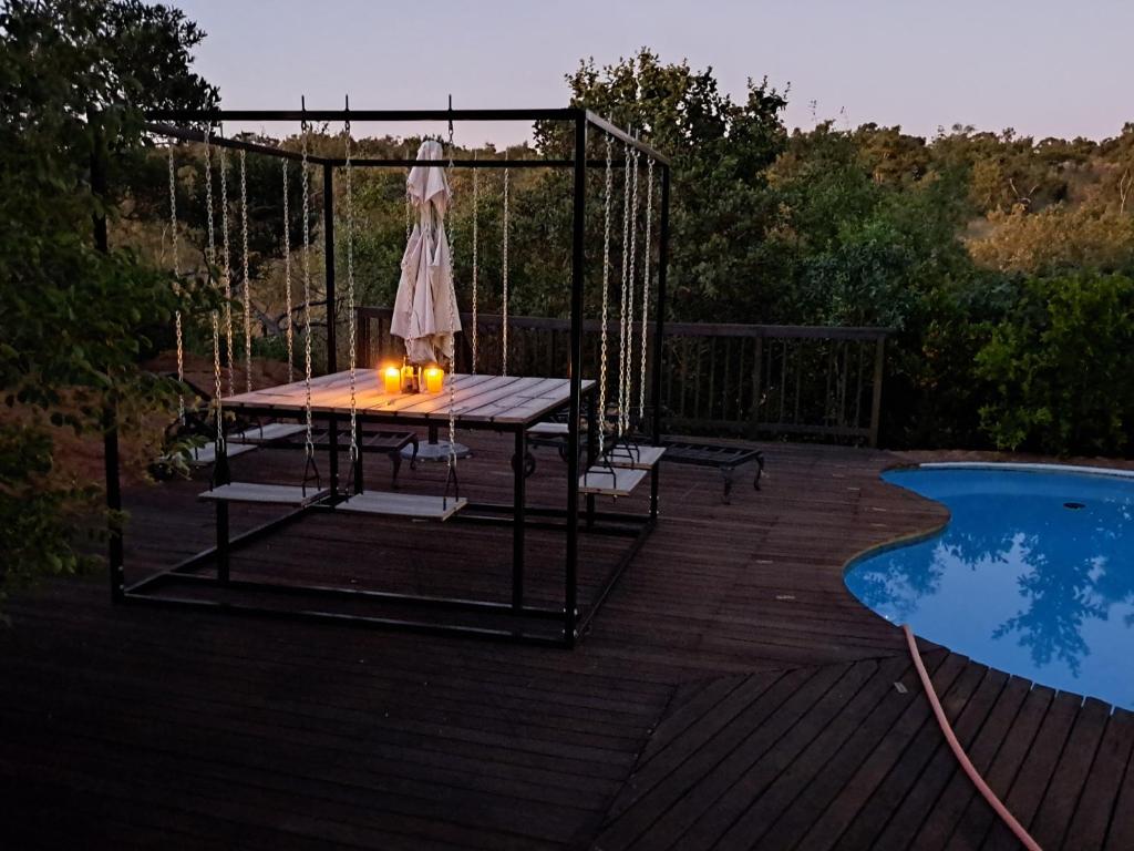 a table on a deck next to a swimming pool at Milkwood Safari Lodge in Warmbaths