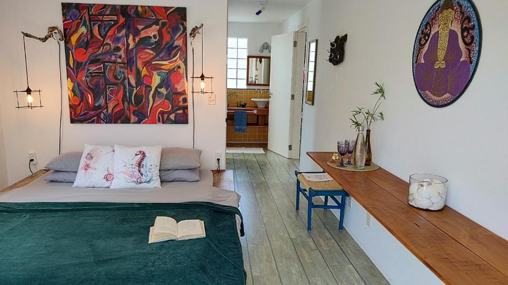 a bedroom with a bed and a table and a painting at Maison de L'ocean Praia 250 m in Florianópolis