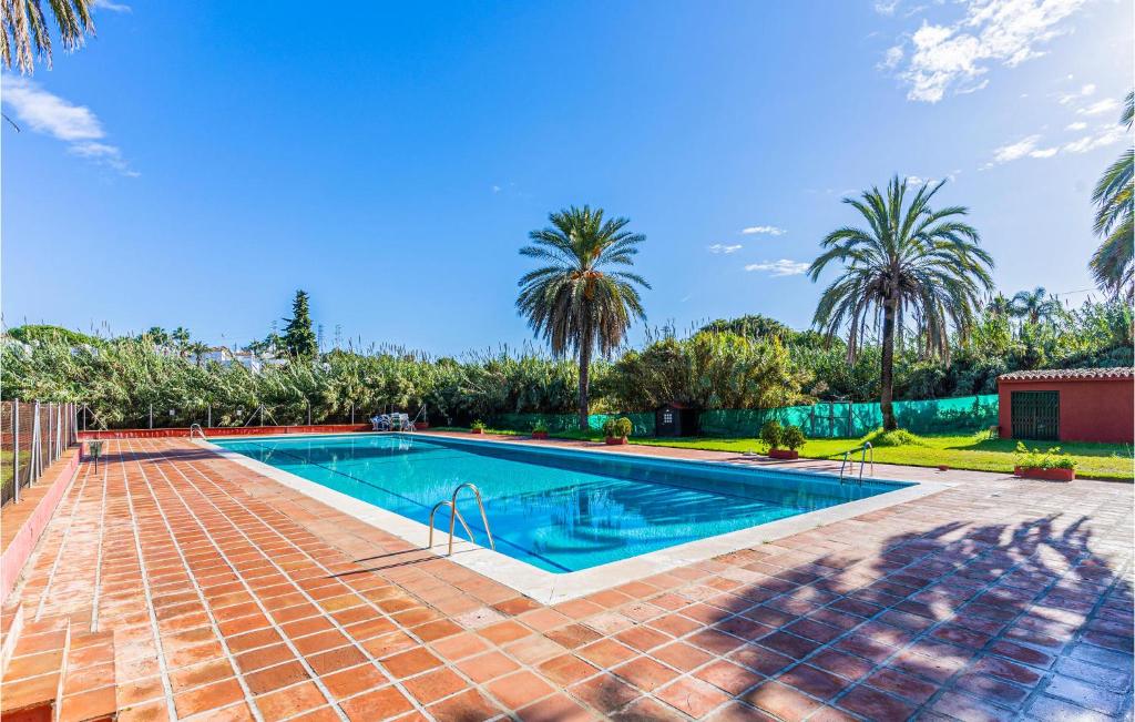 una piscina en un patio con palmeras en Lovely Apartment In Estepona With House A Mountain View, en Estepona