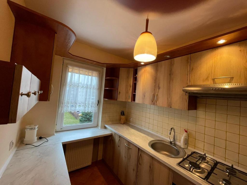 een keuken met houten kasten, een wastafel en een raam bij LUX APARTAMENT in Giżycko