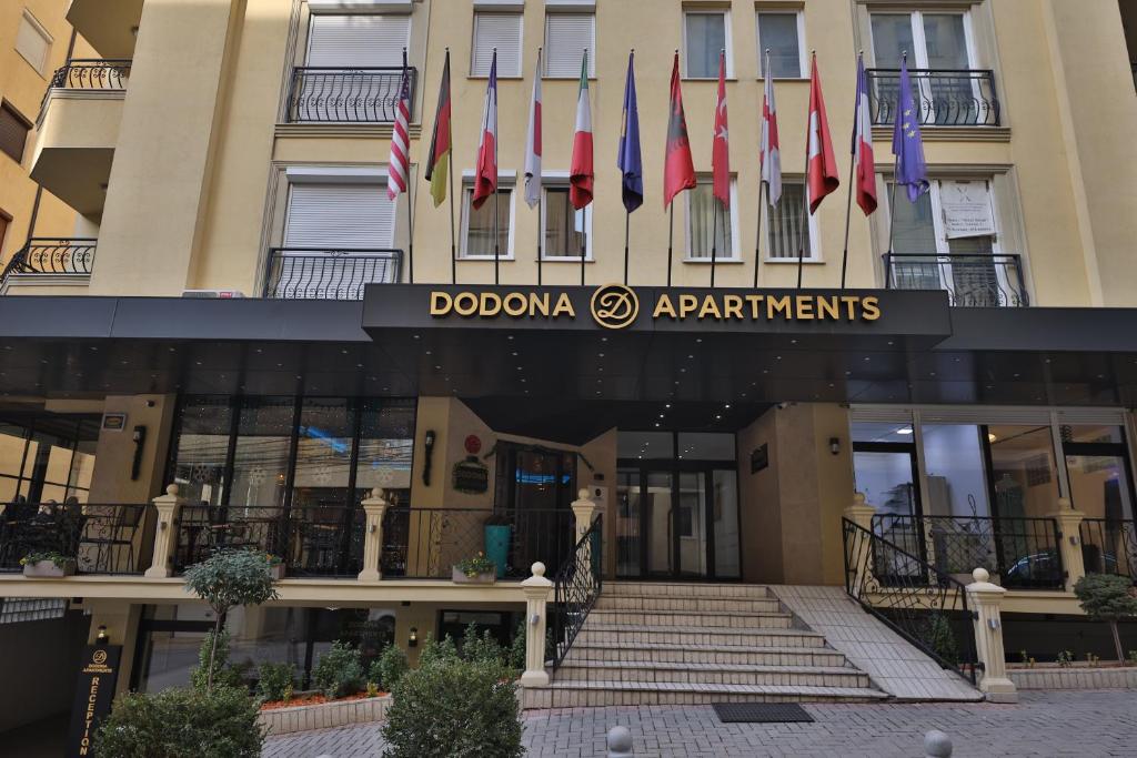 Dodona ApartHotel in Prishtina في بريشتيني: صف من الأعلام على واجهة المبنى