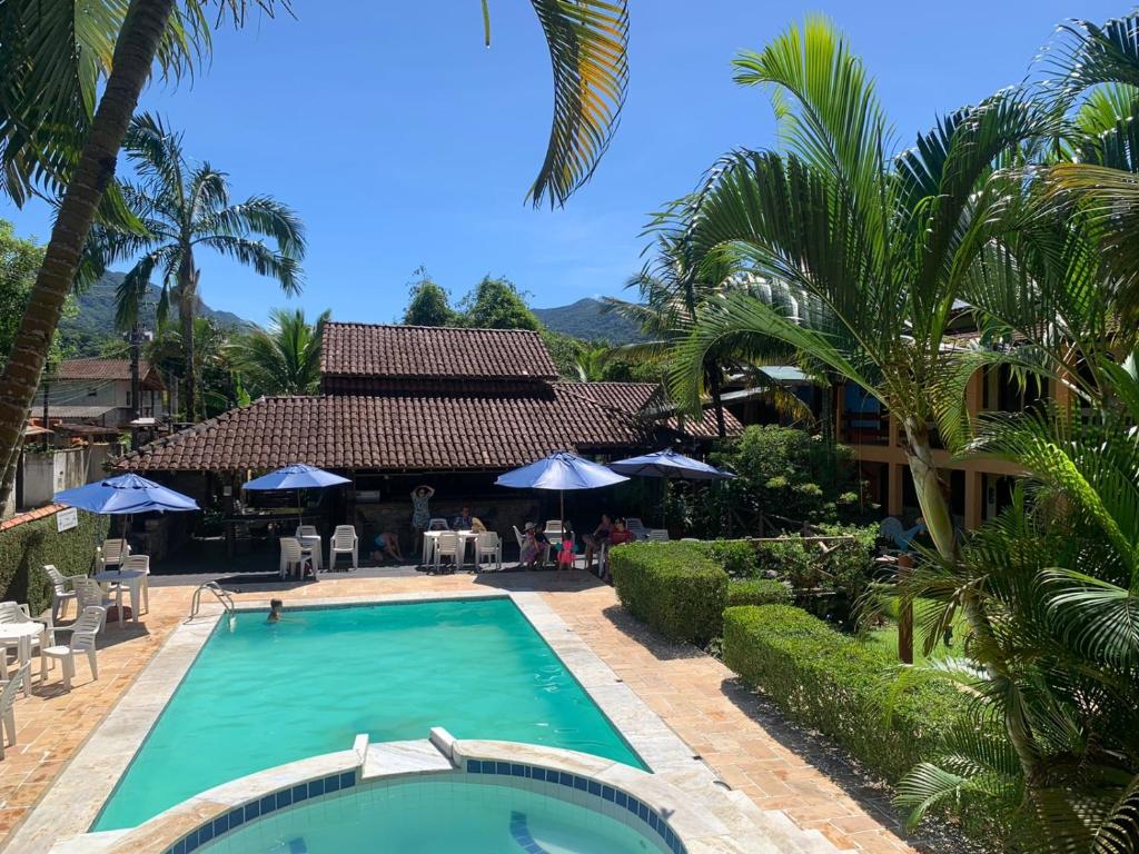 una piscina frente a un complejo con palmeras en Hotel Pousada Cavalo Marinho, en Boicucanga