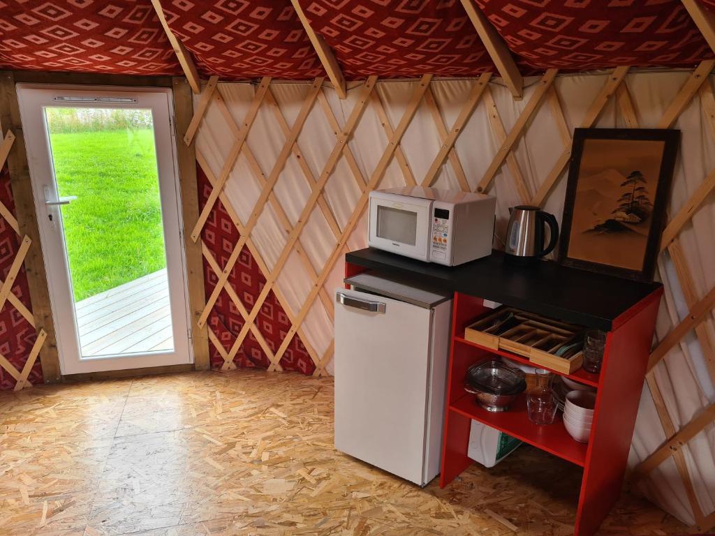 a small kitchen with a refrigerator and a microwave at Camping à la ferme - Hébergements insolites in Cerisy-la-Forêt