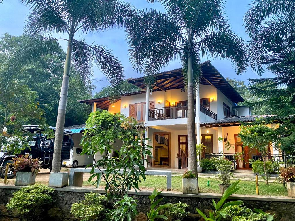 a house with two palm trees in front of it at Mansala Safari House in Udawalawe