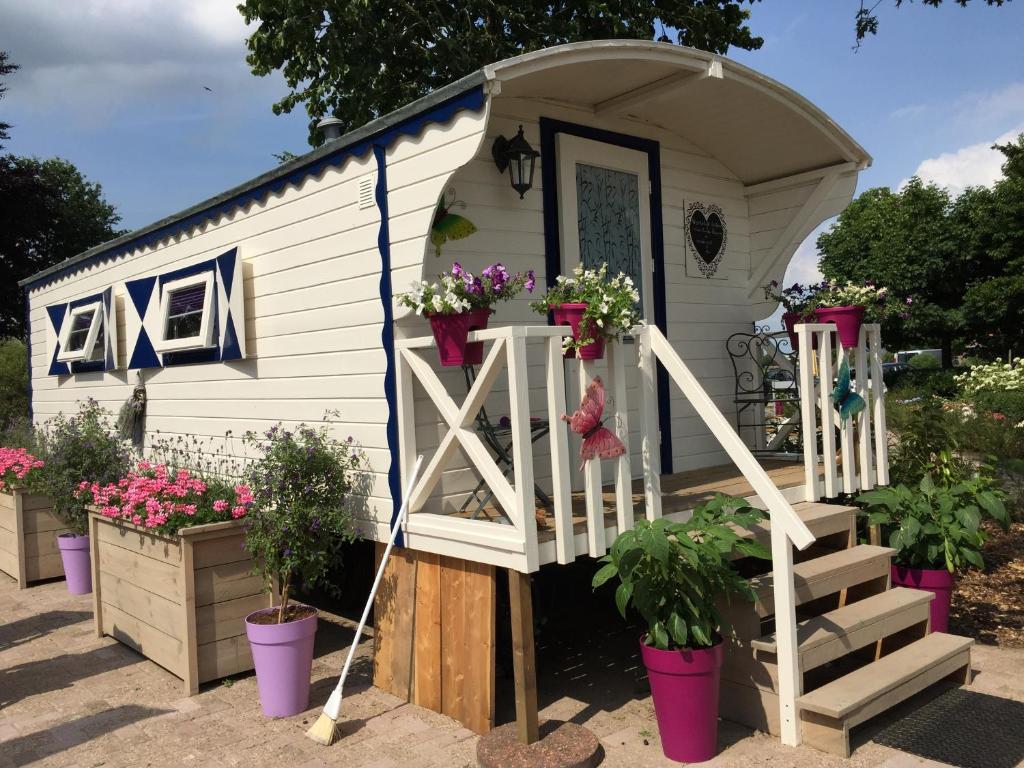 ein winziges Haus mit einer Veranda und Blumen in Töpfen in der Unterkunft Alana Care Bed & Breakfast in Tonden
