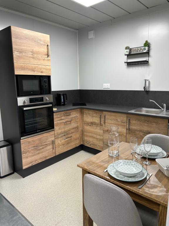 uma cozinha com uma mesa de madeira com cadeiras e electrodomésticos em Les Chambres de Campagne 
