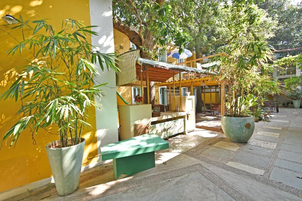 a yellow building with two potted trees and a green bench at Hotel Villa Des Gouverneurs in Puducherry