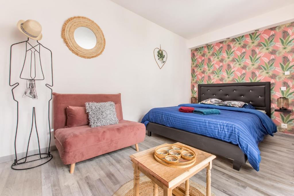 a bedroom with a bed and a chair and a table at Apt Bohème, Parking Privé, Centre in Cambrai