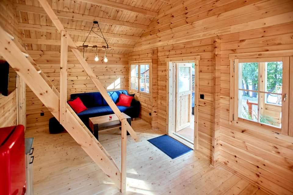 a log cabin with a couch and stairs in it at SŁODKA WODA DOMEK CZERWONY in Lubieszewo