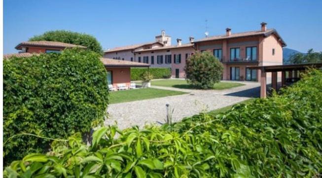 une grande maison avec une cour entourée de buissons dans l'établissement Appartamento Franciacorta, à Cazzago San Martino