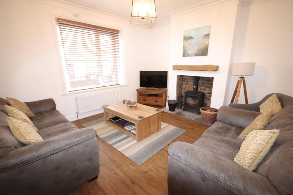 a living room with two couches and a fireplace at Kindly Light Cottage in Amble