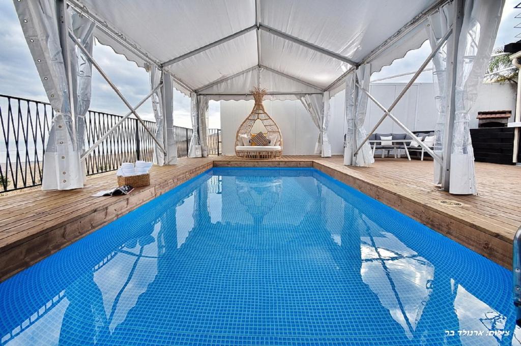 a large swimming pool with a white canopy and a blue pool at Villa Troya in Safed