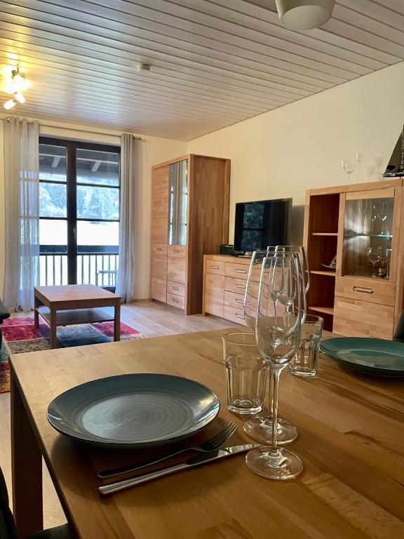 a wooden table with a plate and wine glasses on it at Ferienwohnung am Walchensee in Walchensee