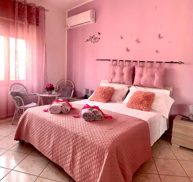 a bedroom with a large bed with pink walls at Butterfly House in Villaputzu