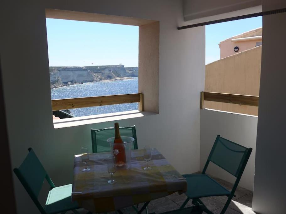 a dining room table with chairs and a window at Duplex sur un fameux Grain de sable in Bonifacio