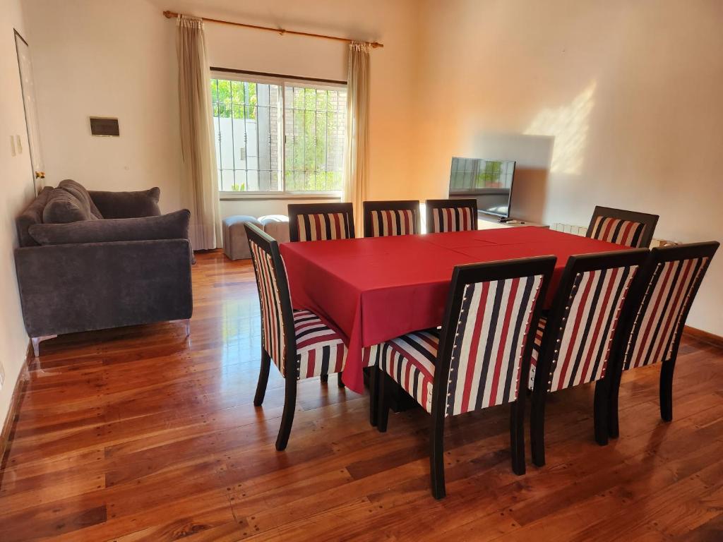 a dining room with a red table and chairs at Casa DELUXE MALBEC , Barrio Privado, con cochera doble, jardín y churrasquera in Mendoza