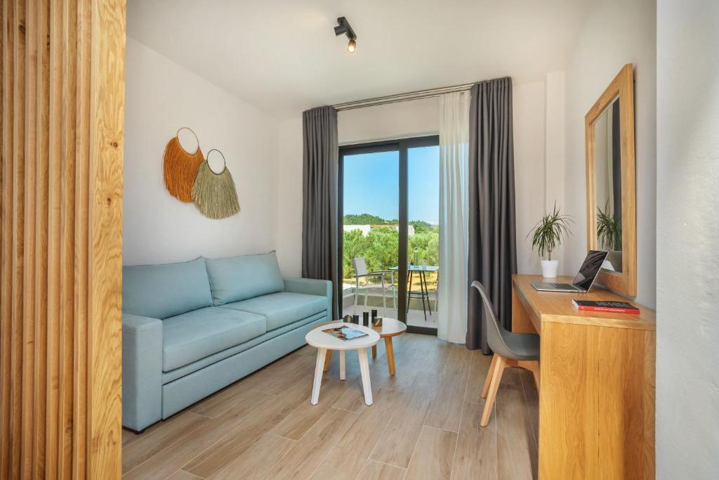 a living room with a blue couch and a desk at AlexMare Hotel Fourka in Skala Fourkas