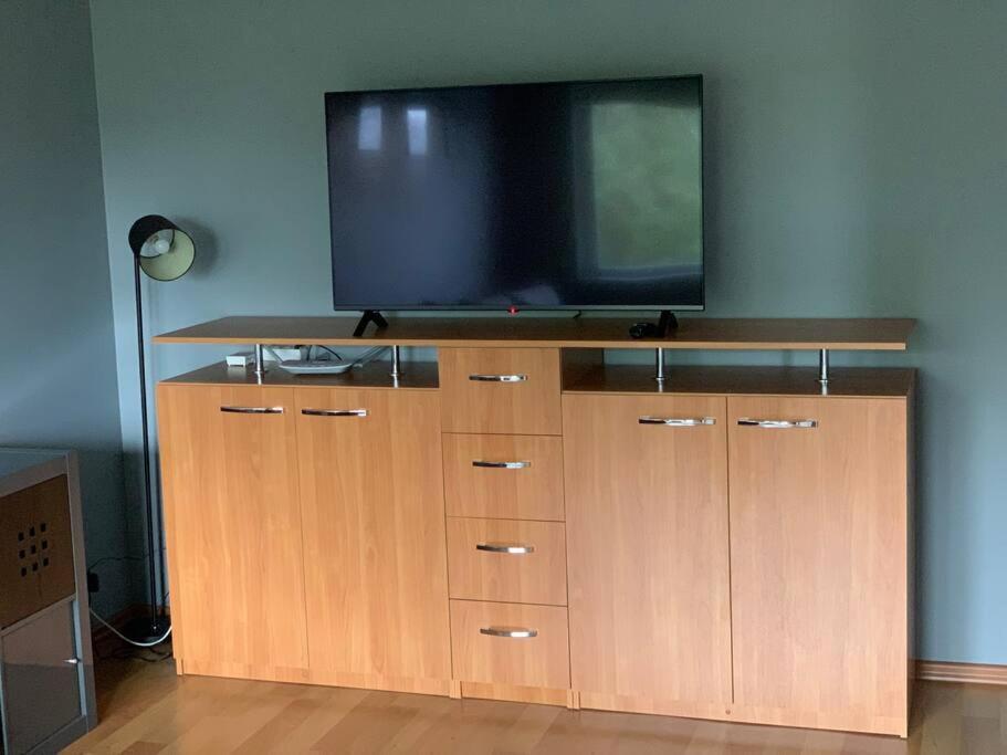 a flat screen tv on top of a wooden entertainment center at Quiet and comfortable apartment with parking for a nice stay for one,two or a couple with a child in Tallinn