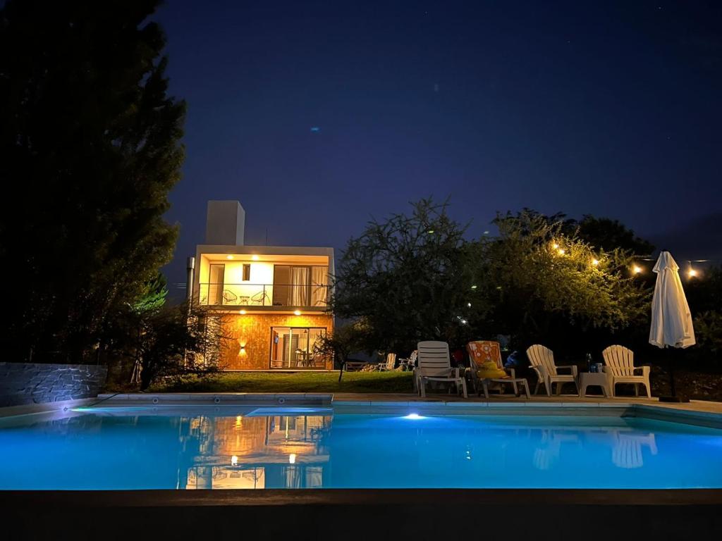 una piscina frente a una casa por la noche en Altos del Espinillo - Casa de Montaña in 