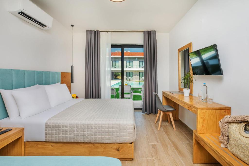 a hotel room with a bed and a desk and a window at AlexMare Hotel Fourka in Skala Fourkas